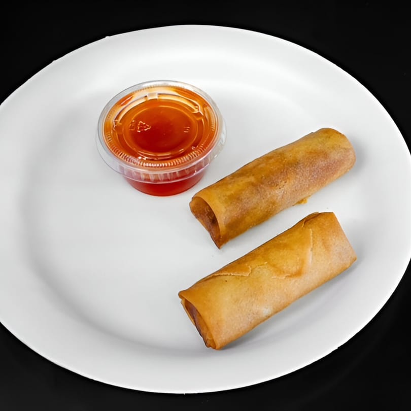 Two golden-brown Chinese egg rolls and a small container of red dipping sauce on a white plate.