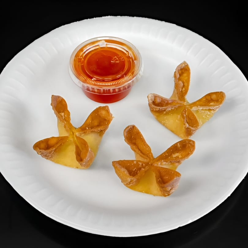 Three golden-brown crab rangoon with a side of sweet and sour sauce on a white plate.