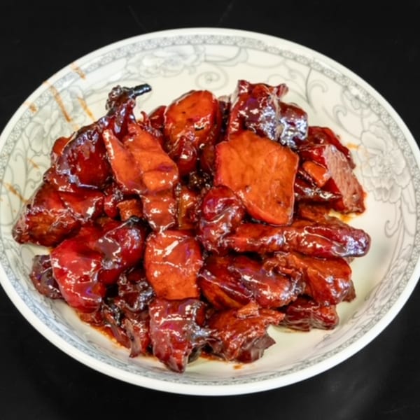 A white plate filled with glistening, dark red chunks of My City Chinese Foods' char siu.