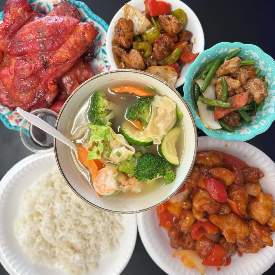 A vibrant spread of Chinese dishes, including red chicken, sweet and sour chicken, and wonton soup.