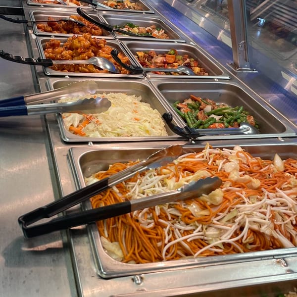 A buffet line at My City Chinese Foods with various dishes, including noodles, orange chicken, and green beans.