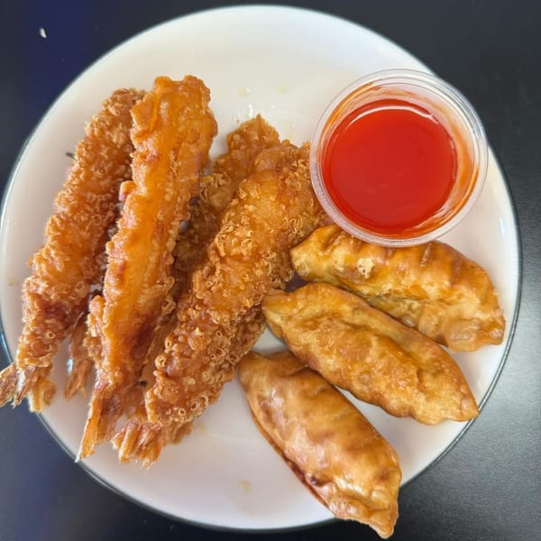 Crispy fried shrimp and dumplings with a side of red dipping sauce on a white plate.