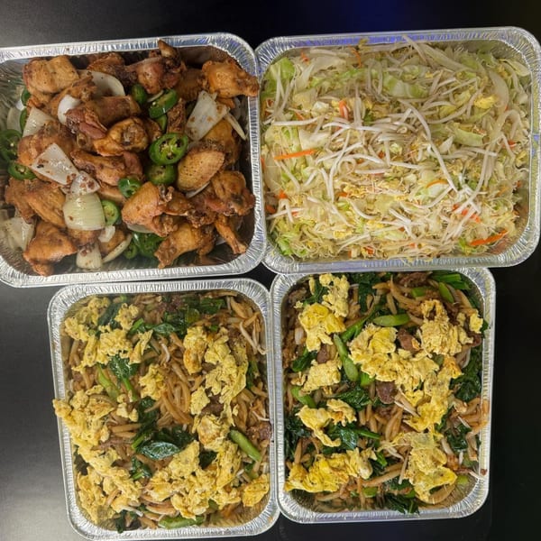 Four foil containers of Chinese food, including fried chicken wings, chow mein, and mixed vegetables.
